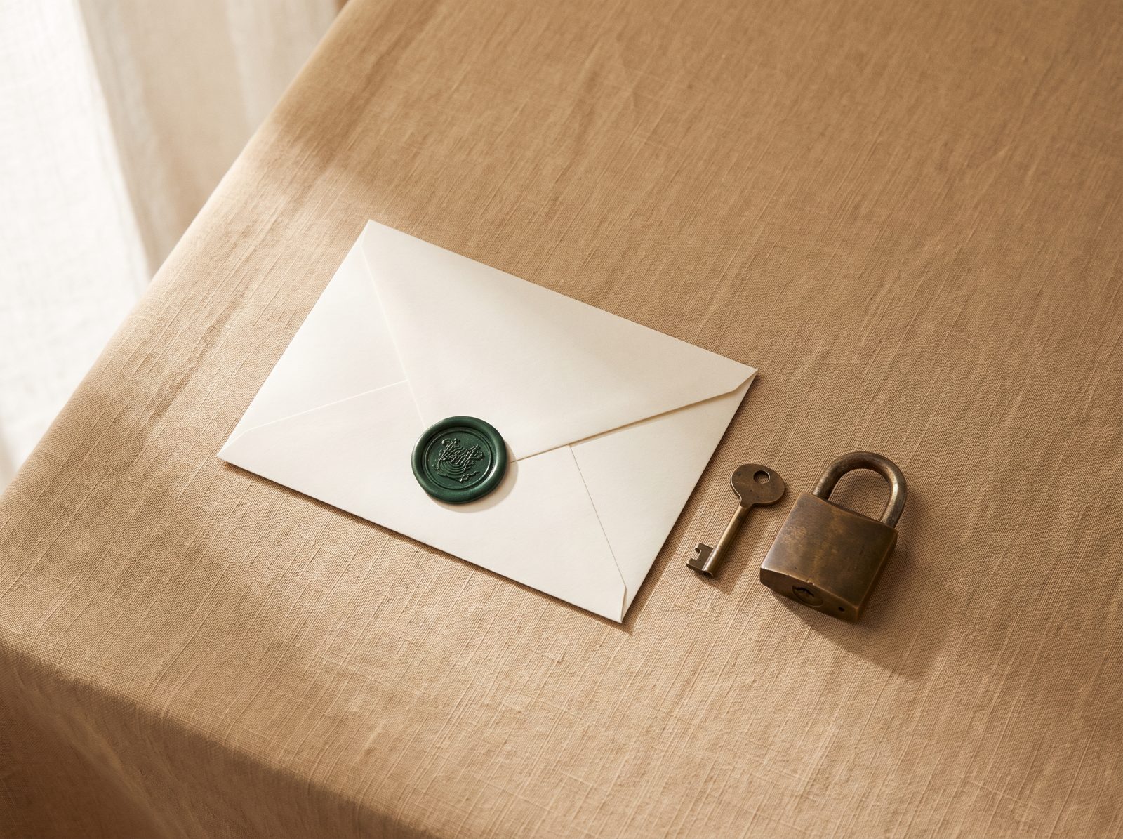 A sealed envelope with a green wax seal beside a key and a padlock